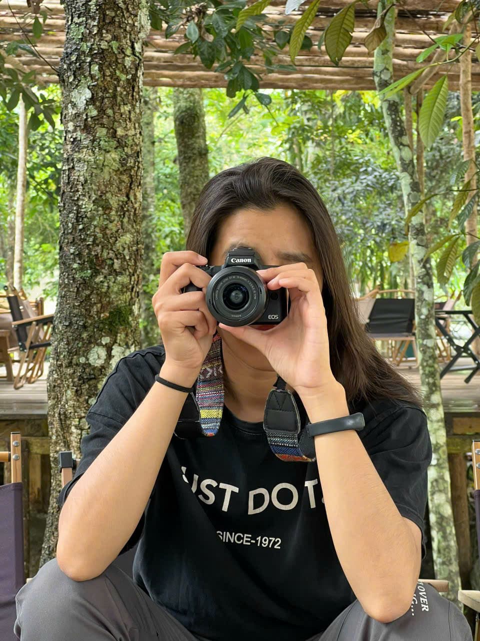Hazel Dinh holding a camera among the trees
